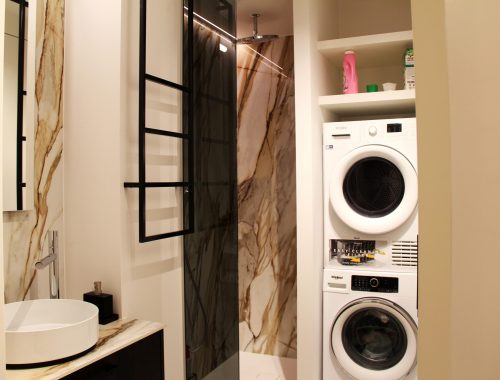 Een wasmachine en droogkast in een luxueuze badkamer