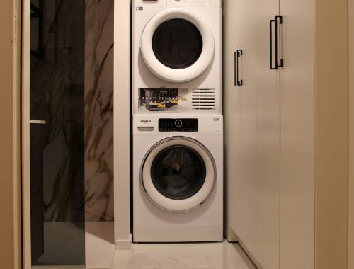 Een close up van een wasmachine en droogkast in een luxueuze badkamer